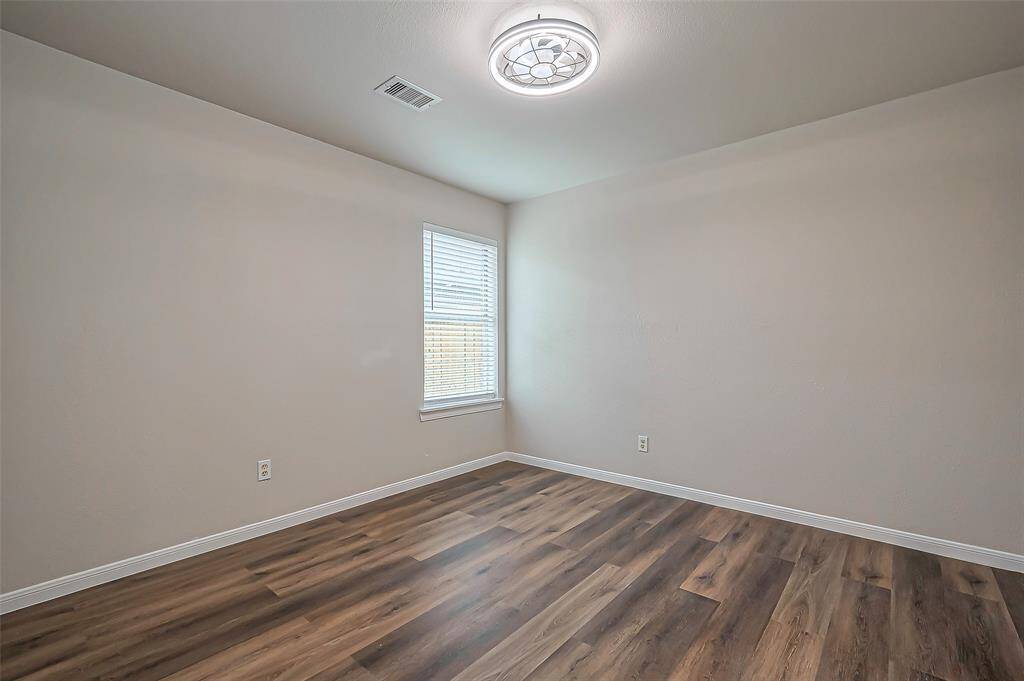 Bedroom #2 measures 11.1 x 10.11 and features a window with 2-inch blinds overlooking the side yard. A modern ceiling fan with a remote (2024) adds comfort, while the durable LVP flooring provides a sleek and low-maintenance finish.