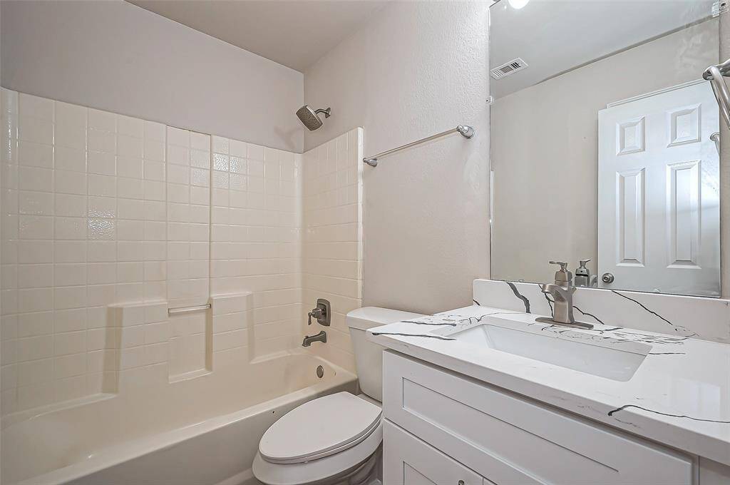 Between Bedroom #2 and Bedroom #3 is a full bathroom (Bath #2), featuring a single undermount sink in a sleek quartz vanity with an updated faucet. A wall mirror and Hollywood lighting add style and brightness to the space. The bathroom includes a cultured marble combination tub and shower, along with a linen closet for additional storage.