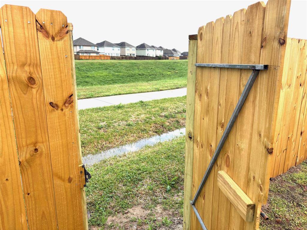 The gate leads to a concrete walking path directly behind the property, offering easy access to outdoor activities and a scenic route for walking or biking.