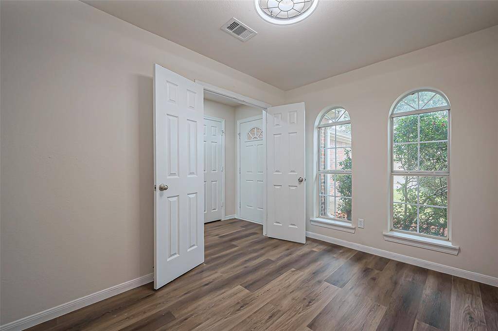 French doors open to a versatile home office or study, featuring a pair of elegant arched windows that overlook the front of the home. A newly installed ceiling fan (2024) adds comfort. The doors provide privacy, making it an ideal space for working from home, especially during conference calls or Zoom meetings.