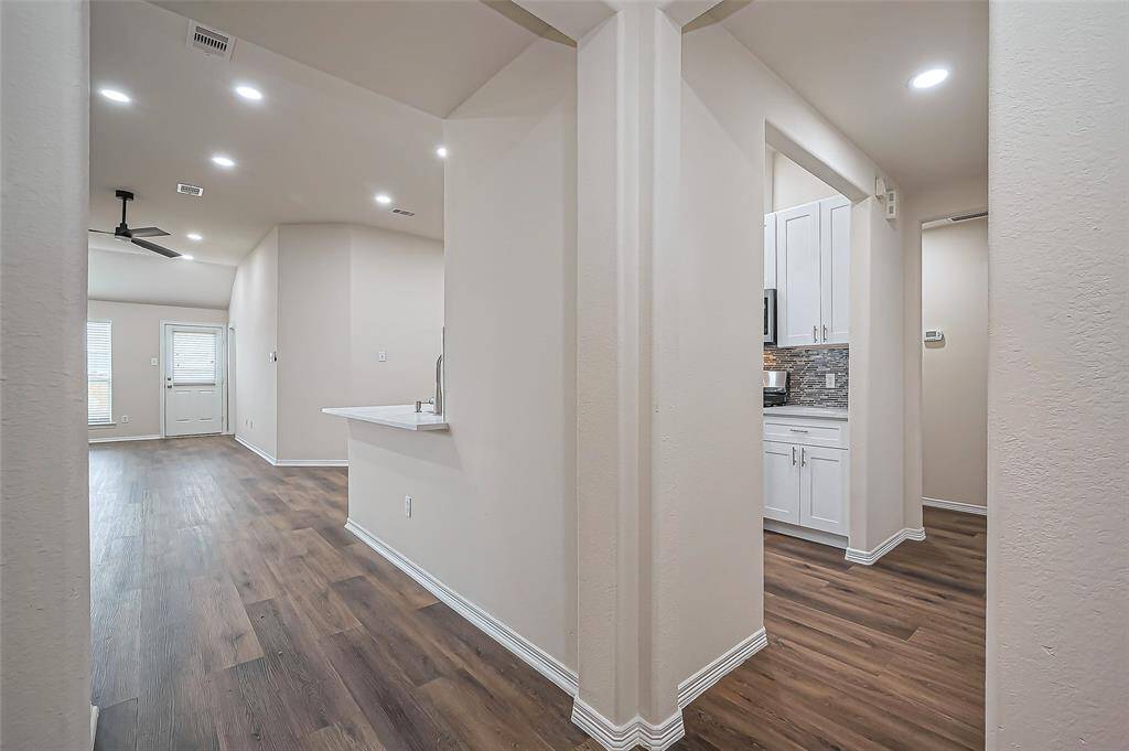 The foyer flows into an open-concept family room and kitchen on the left, creating a seamless space for gathering and entertaining. To the right, a hallway leads to two secondary bedrooms. The open layout enhances natural light and connectivity, making it ideal for everyday living.