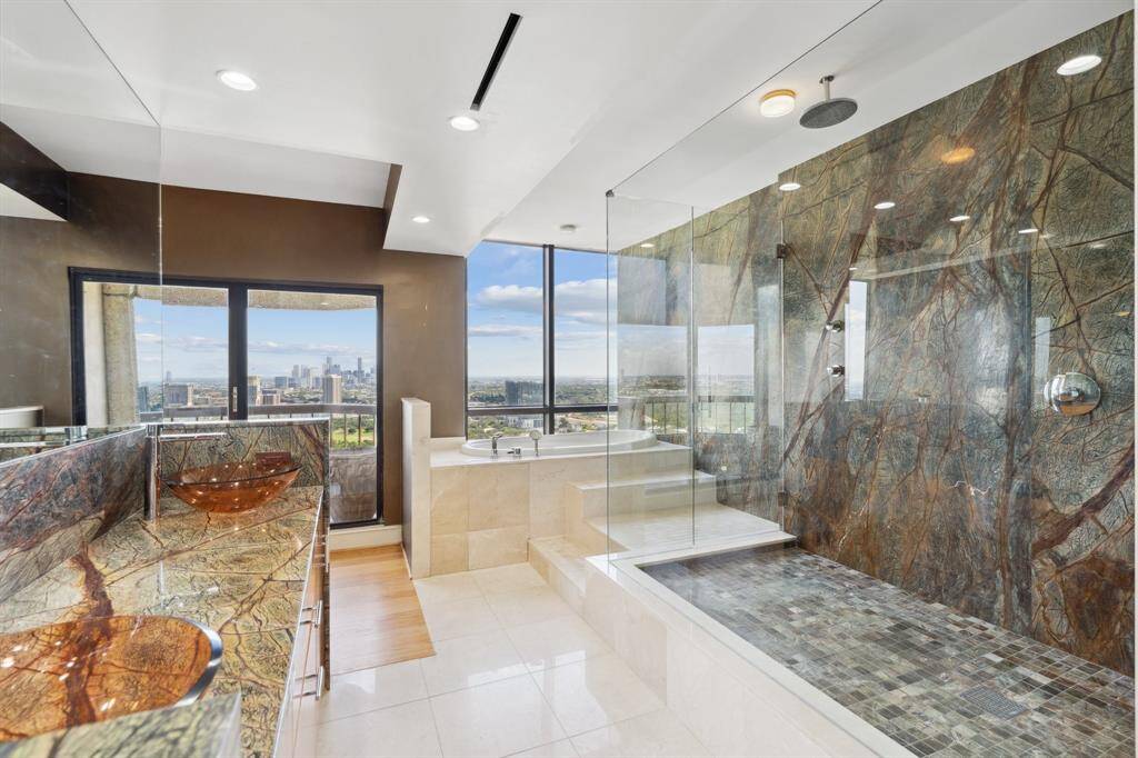 Primary bathroom with double sink vanity, oversized seamless glass shower and balcony access.