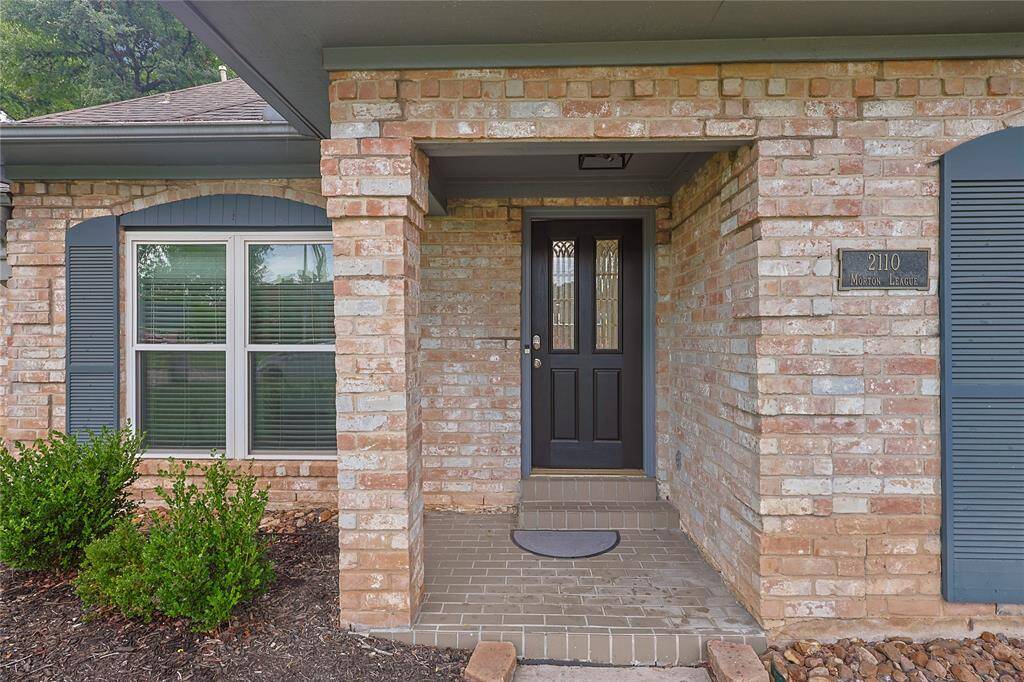 Charming brick exterior with a welcoming covered entryway. Features a modern front door and large windows with shutters. Low-maintenance landscaping enhances the inviting curb appeal.