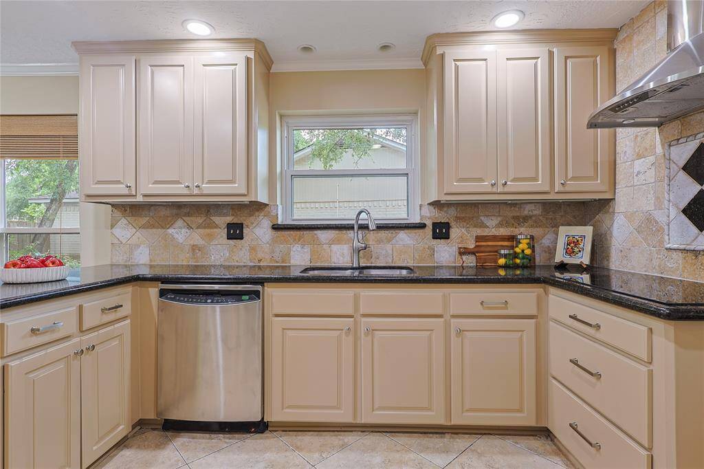 This kitchen features elegant cabinetry with a neutral tone, granite countertops, and a stylish tile backsplash. It includes stainless steel appliances and ample natural light from the window above the sink. Think of the great meals you will create....