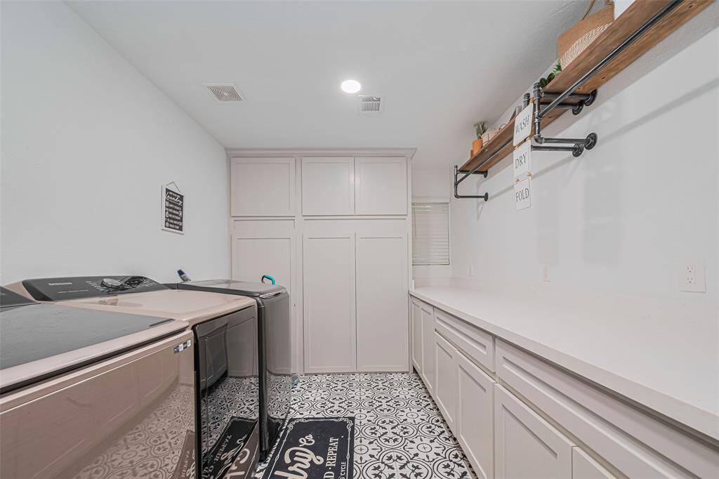 This laundry room features ample storage with sleek cabinetry, and a stylish patterned floor.