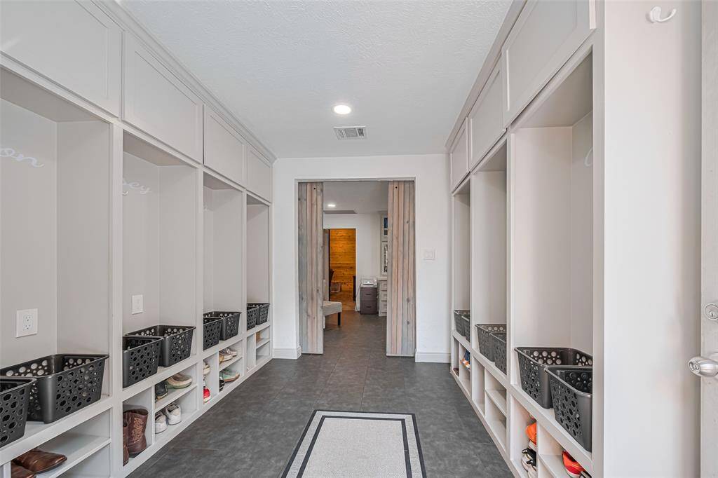 Spacious mudroom with built-in cubbies, perfect for organizing shoes and personal items. The neutral color palette and recessed lighting create a bright and welcoming atmosphere from the side door.