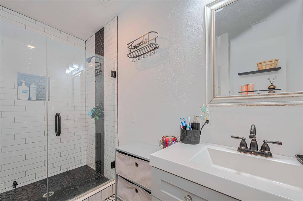 Modern bathroom with a sleek glass shower, white subway tiles, and a stylish dark tile floor.