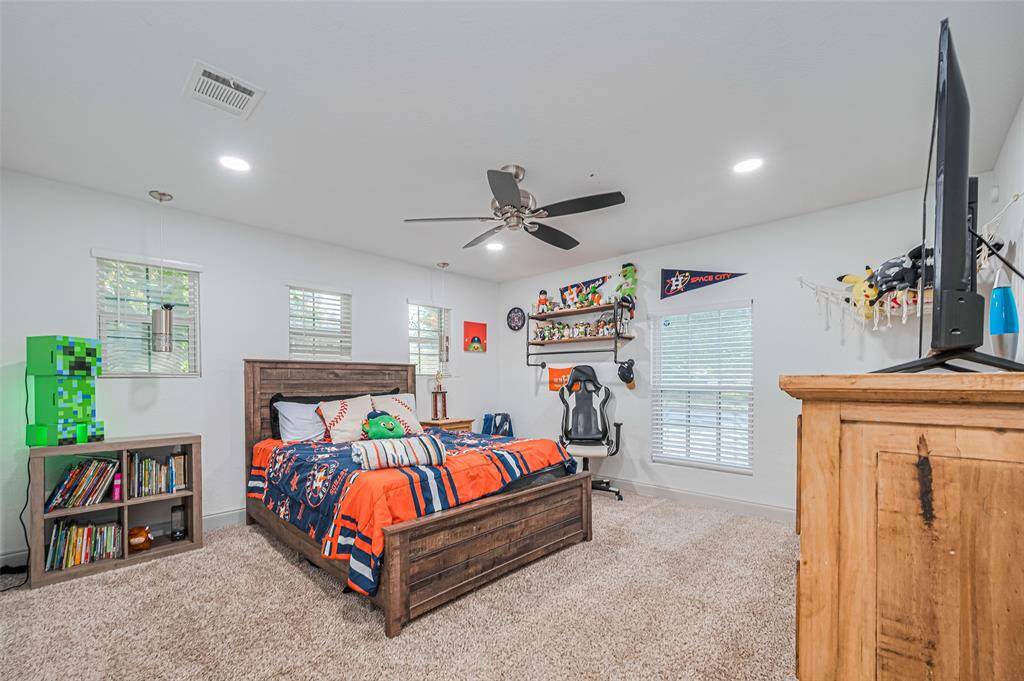 This is a bright, spacious first-level bedroom with carpeted floors and modern recessed lighting.