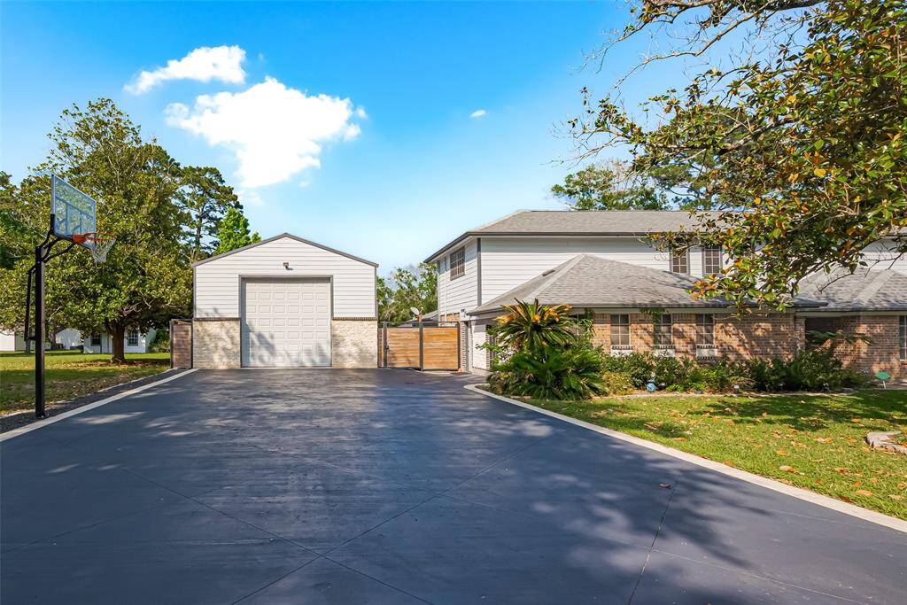 This property features a spacious driveway with a basketball hoop, leading to a large detached garage or workshop, offering ample space for vehicles and storage.