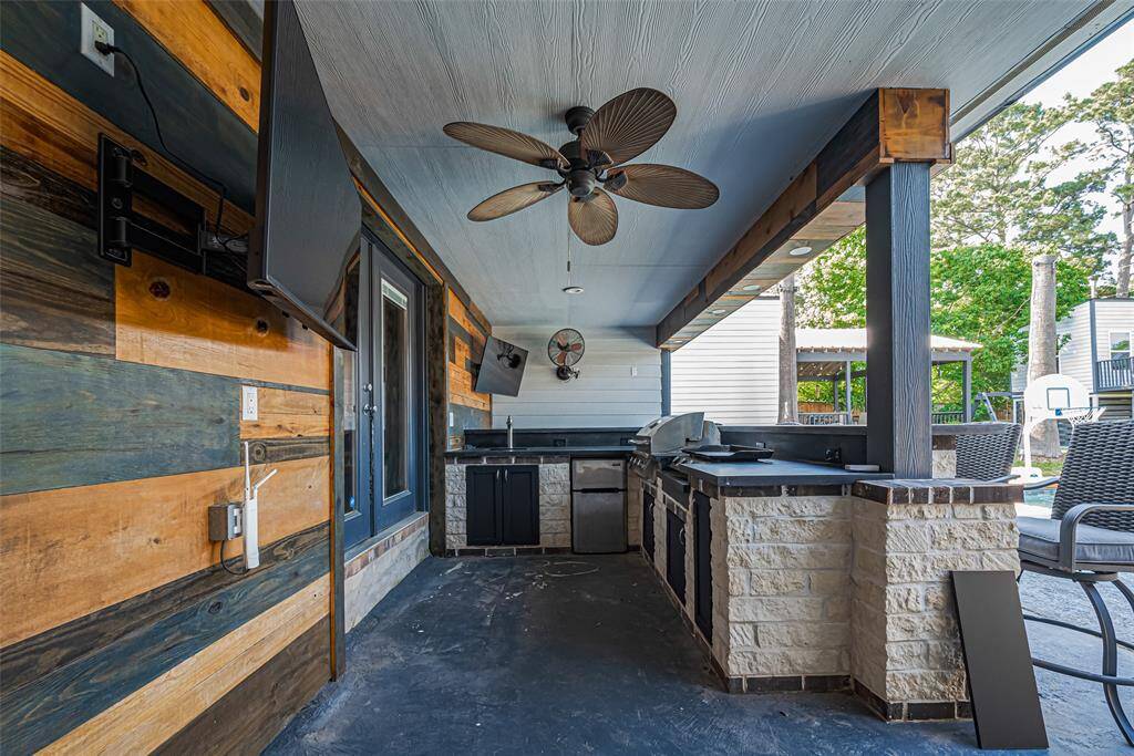 Stylish outdoor kitchen with modern amenities. The space features a rustic wood and stone design, and a large bar area providing a versatile outdoor living experience perfect for entertaining.