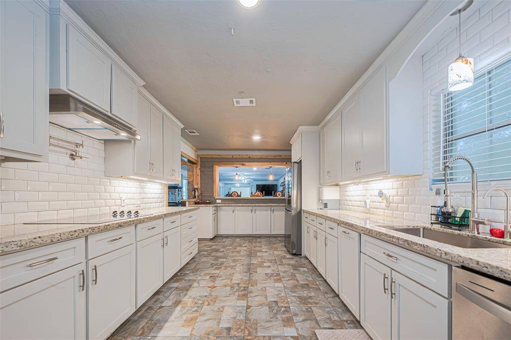 This spacious kitchen features modern white cabinetry, sleek granite countertops, and a stylish tile backsplash.