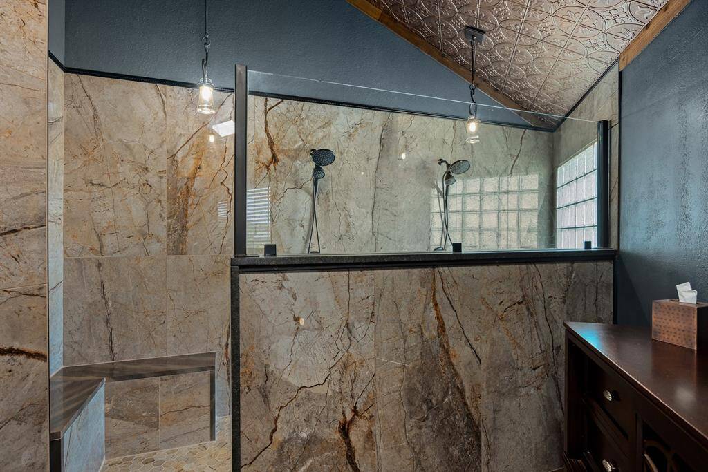 Primary bathroom features 12' long custom marble shower place with dual shower heads, a matching granite seat, a 48' hidden shampoo niche, a custom glass partition, and a glass block wall.