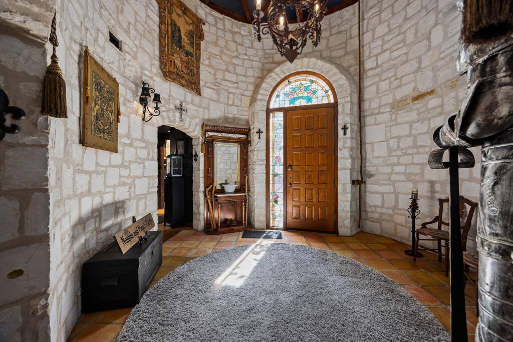 Breathtaking grand foyer features stoned round entryway, 21' vaulted ceiling with custom wood beams & French castle iron chandelier.