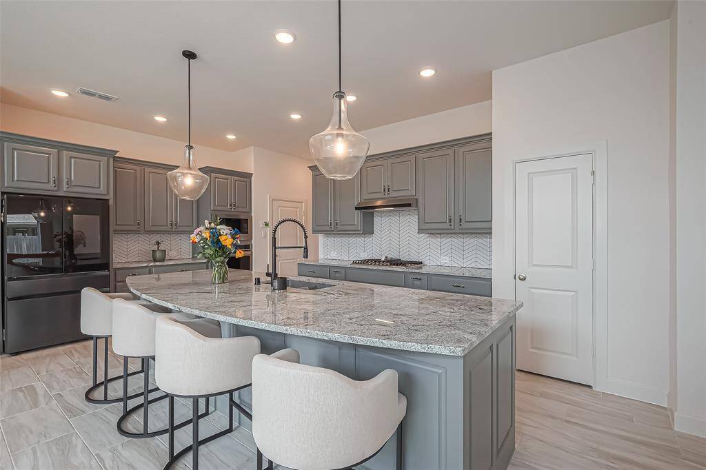 The kitchen also features two beautiful pendant lights, matte black faucet, 5-burner gas stove, breakfast bar area and in-wall oven and microwave.
