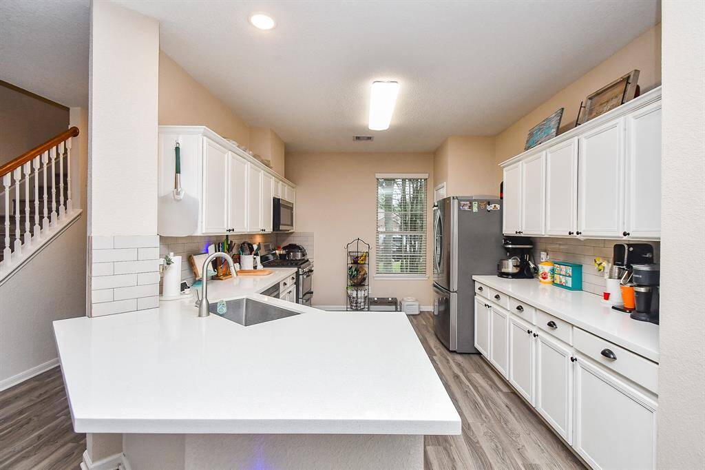 Bright, modern, open kitchen with white cabinetry, stainless steel appliances, and ample counter space