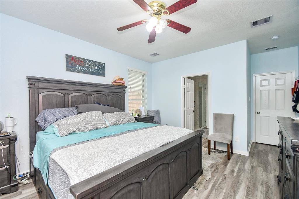 The primary bedroom features a spacious layout with an en-suite bathroom. Ceiling fan with lights, a window for natural light creates a cozy atmosphere