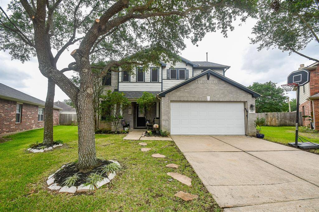 The house is surrounded by mature trees, providing ample shade, and includes a well-maintained front lawn.