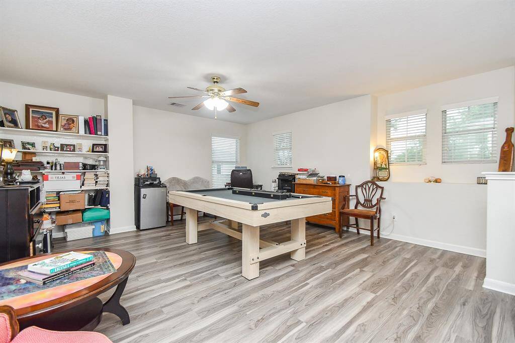 This spacious game room features a ceiling fan, built-in shelves and lots of natural light from multiple windows