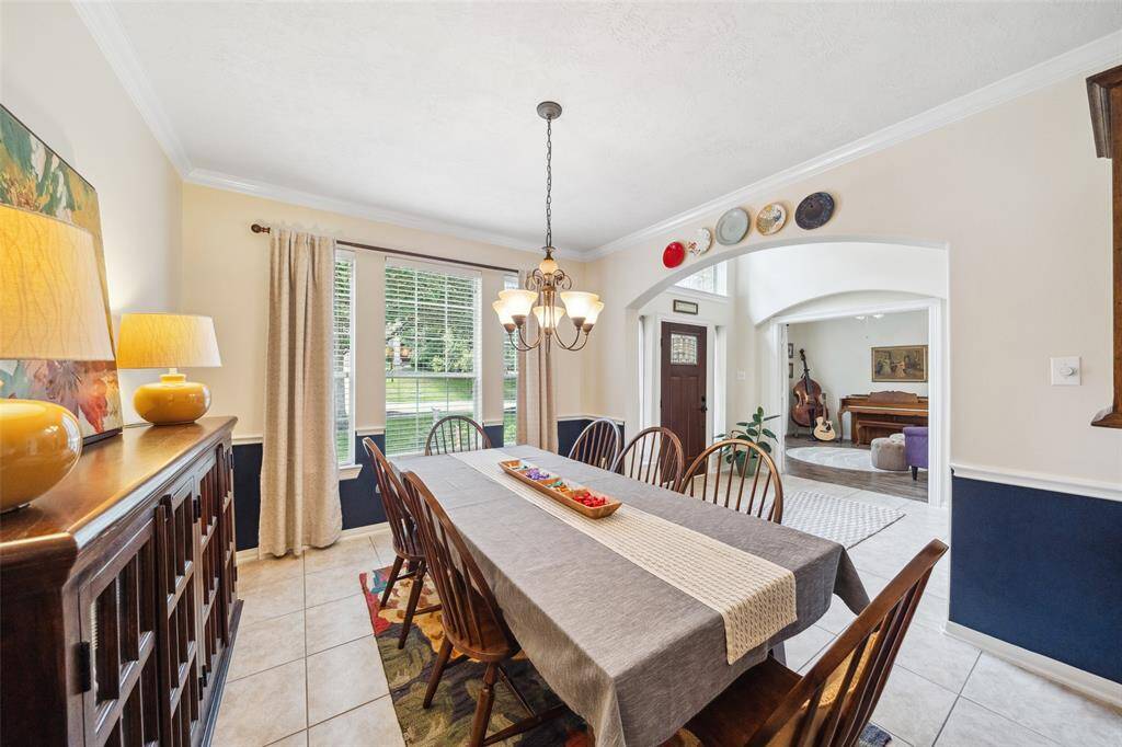 This dining area features large windows for natural light, a cozy atmosphere with a large dining table that accommodates large gatherings, and elegant lighting.