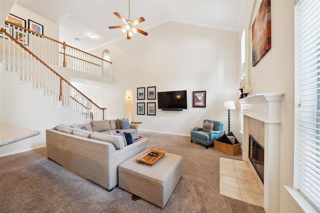 Spacious living room with high ceilings, featuring plenty of room for oversized furniture. The room has a neutral color palette, large windows for natural light, and an open staircase leading to a loft area.