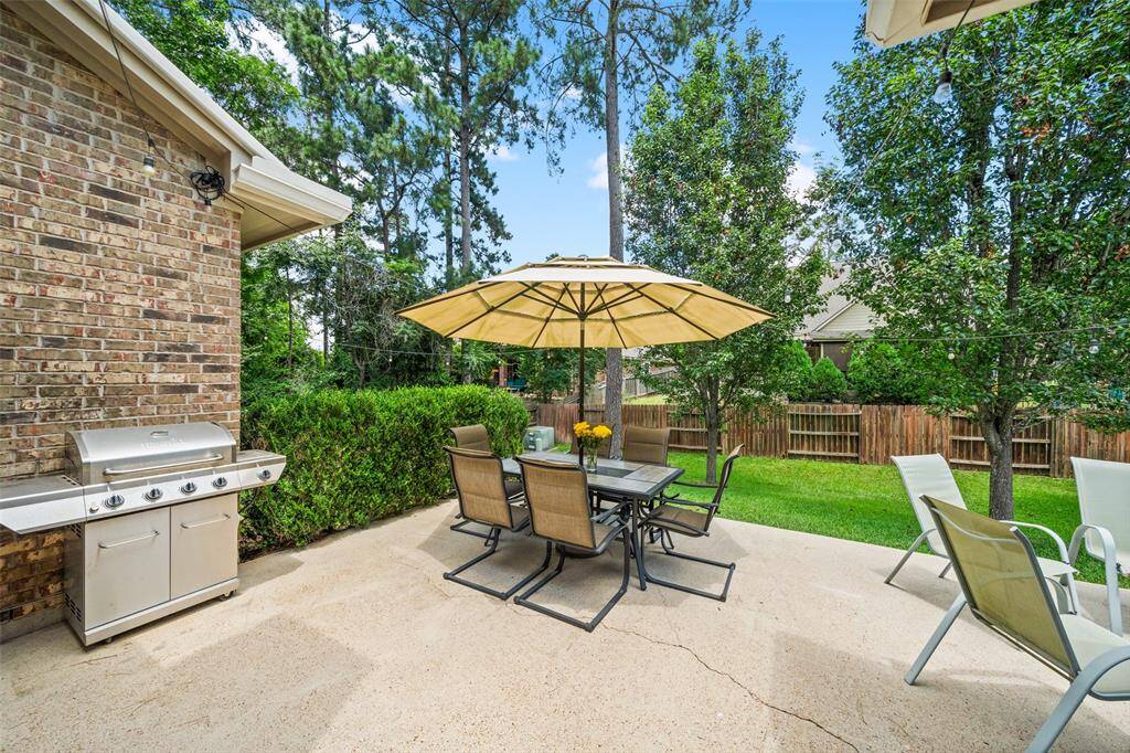 This inviting backyard features a spacious patio and lush greenery with mature trees, ideal for outdoor entertaining and relaxation.