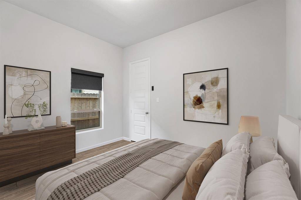 This beautifully designed bedroom features custom paint, a large window with sleek roller shades, and stylish wood-look tile flooring for a modern and cozy feel!