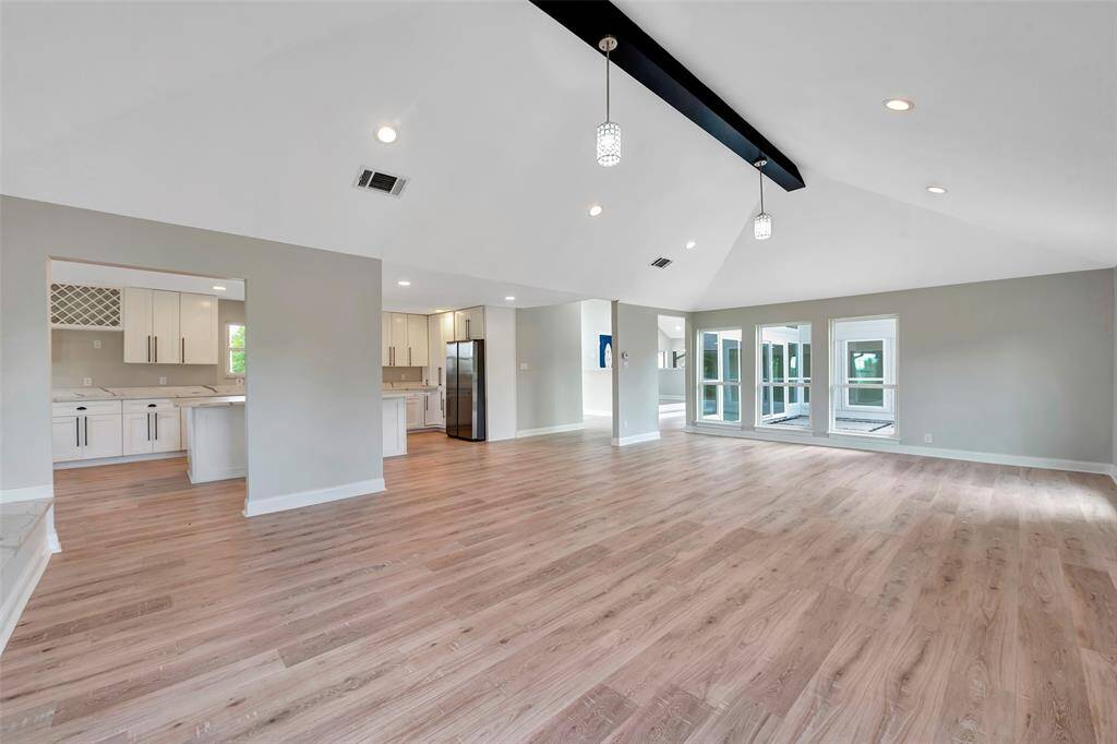 The expansive living room offers a dramatic center wood beam ceiling with pendant lights in addition to recessed lighting.