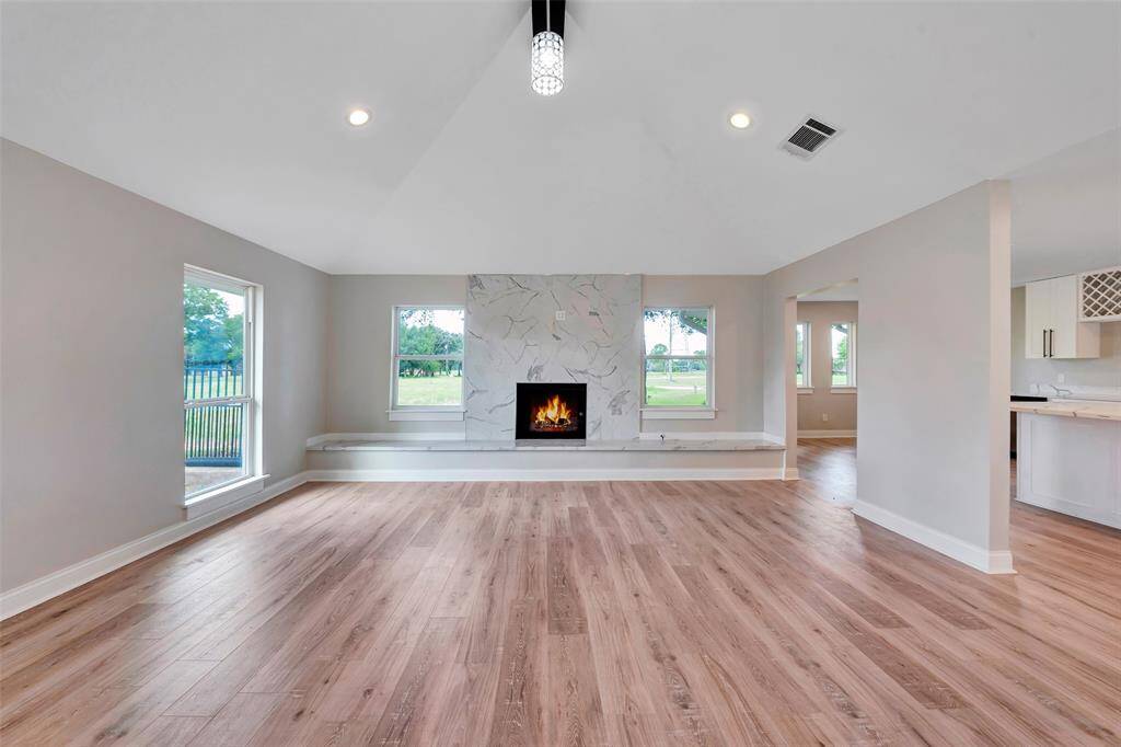 Impressive wall with fireplace is the visual anchor to this grand gathering space! Recently (2024) remodeled with extensive tile surrounding the gas log fireplace with sitting areas and windows on each side.