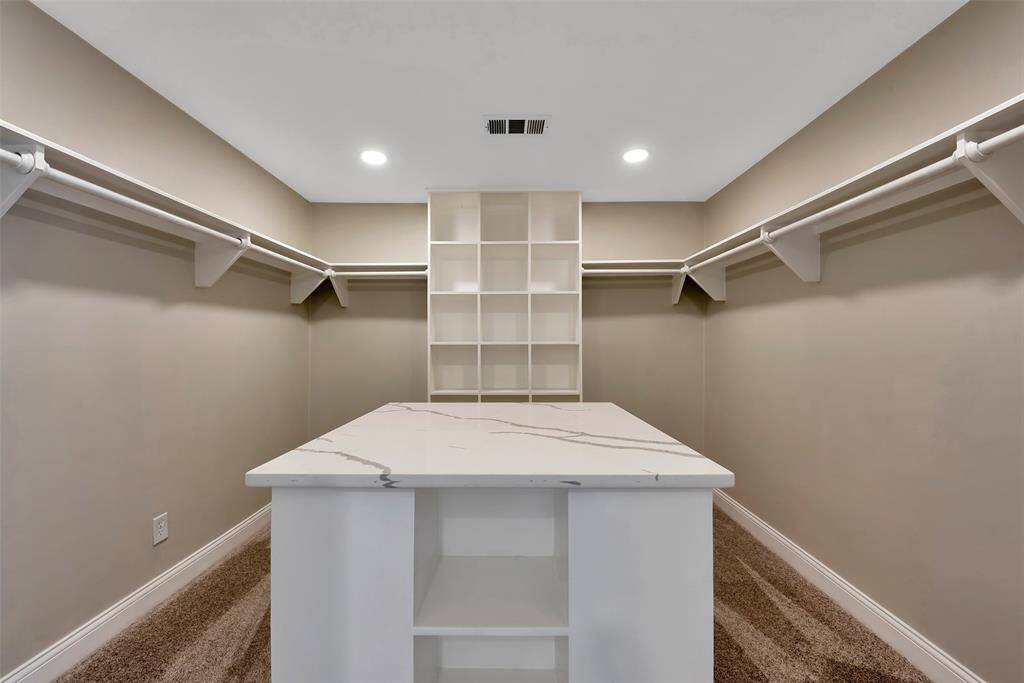 Primary walk-in closet with convenient center island and lots of great built-ins.