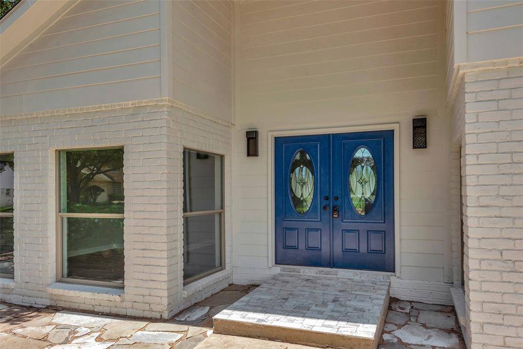 The welcoming entrance with bright blue doors that contrast nicely against the white brick and exterior siding! Modern exterior lighting and flagstone accents!
