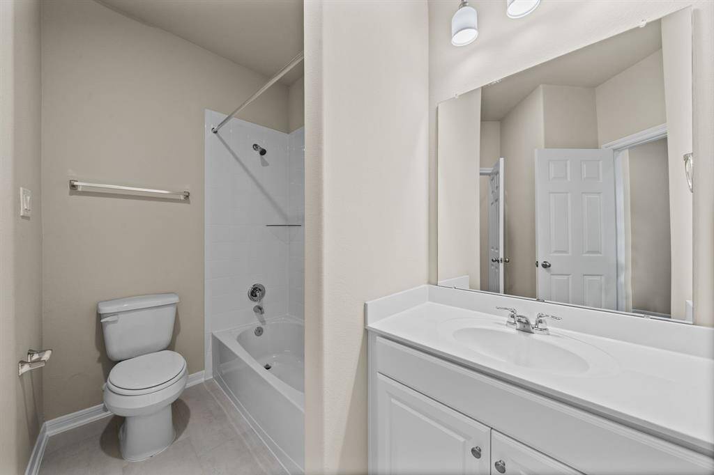 The secondary bath features tile flooring, white cabinetry and light countertops and a shower/tub combo. Perfect for accommodating any visiting family and friends.