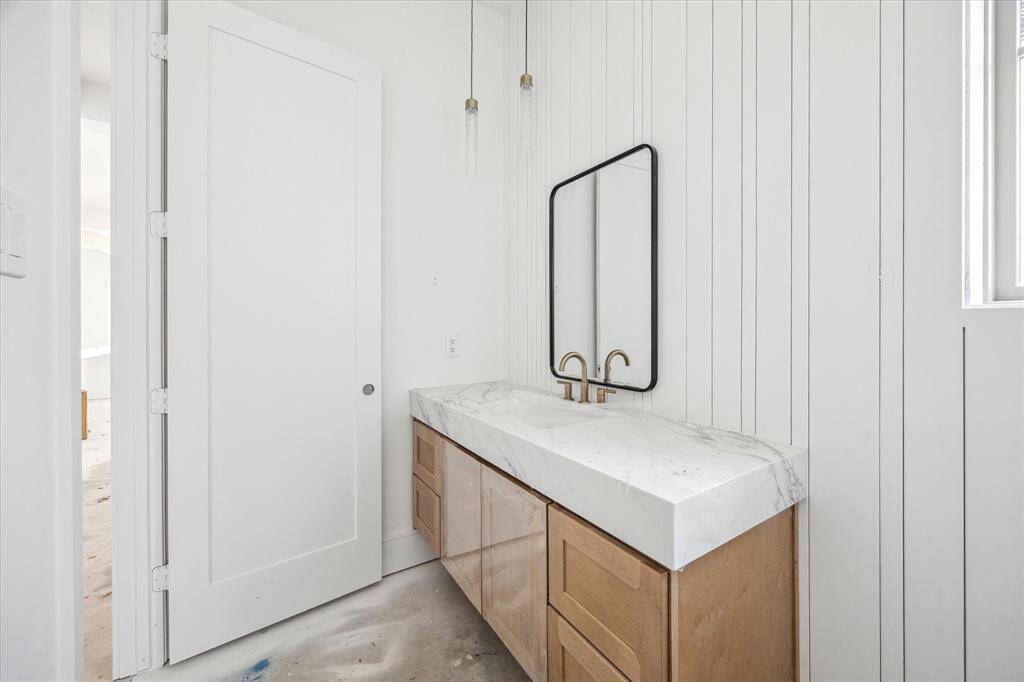 First-floor powder off the entry with 5" Quartz countertops, paneled vanity feature wall, and pendent lights.