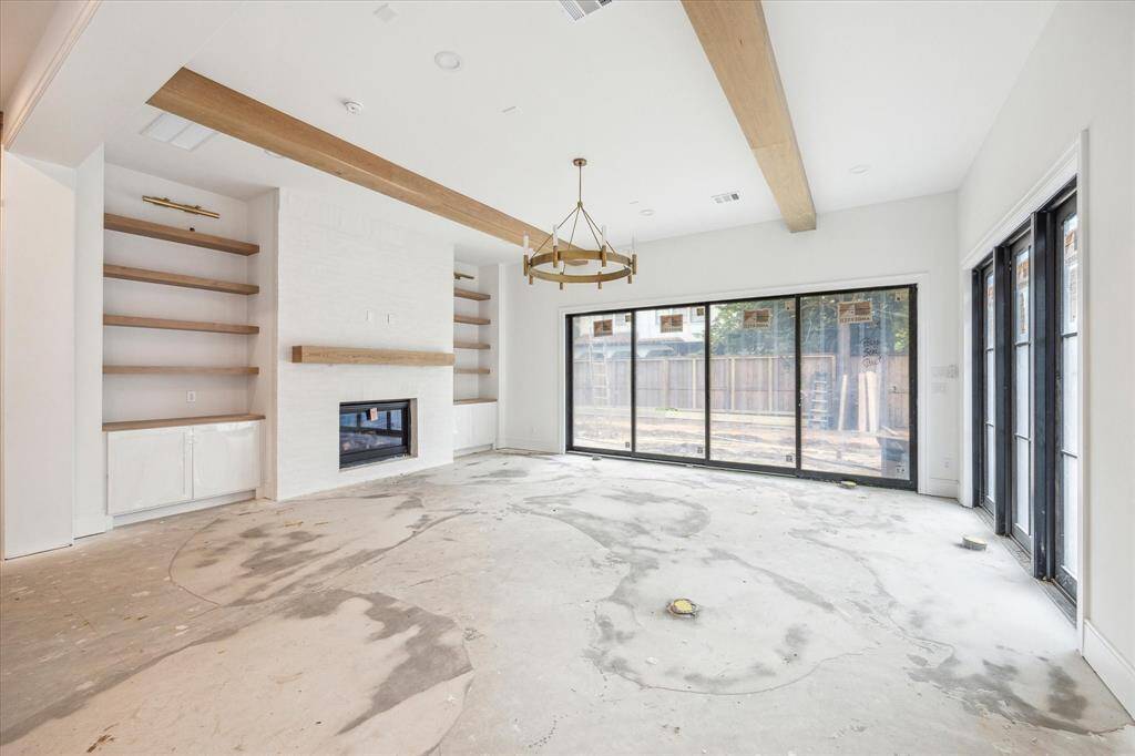 Custom mantel and cabinetry with overhead sconces surround the gas fireplace with German Schmear detail work. Chandelier and 10"" White Oak beams complete this space.