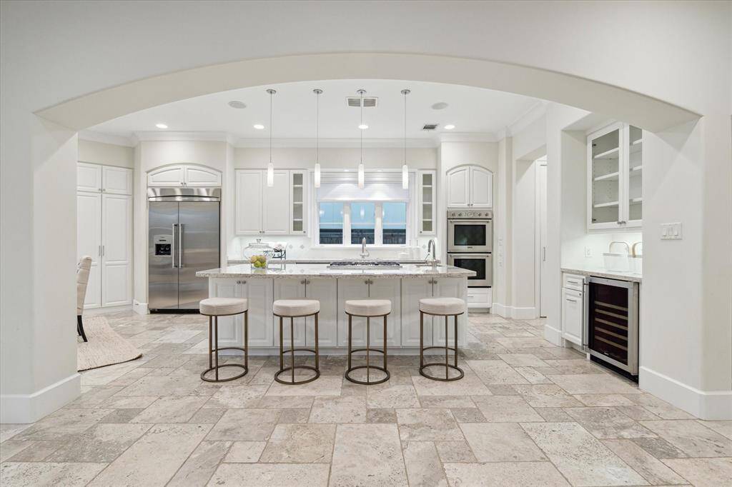 The generous kitchen boasts a large granite island, Thermador gas cooktop, dual ovens, and dual Asko dishwashers.