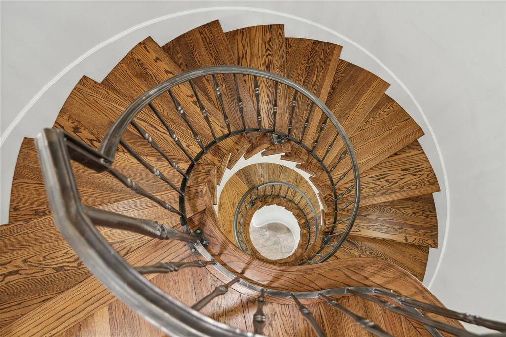 This photo showcases a beautifully crafted spiral staircase with rich wooden steps and elegant metal railings, offering a stunning architectural feature for the home.