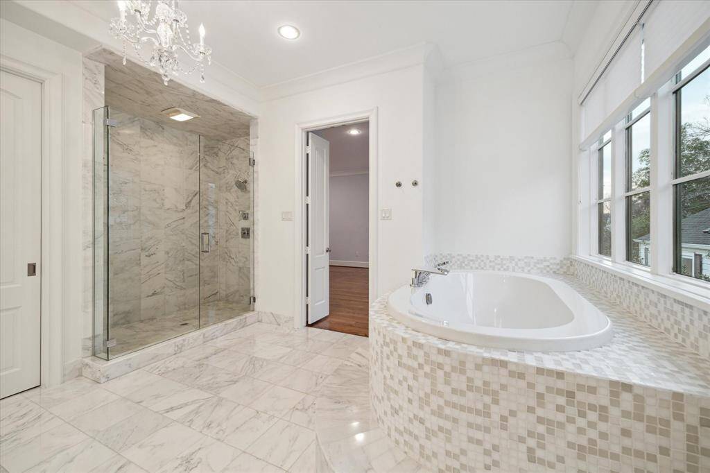 Luxurious primary bathroom with elegant marble finishes, a spacious walk-in shower, and a relaxing soaking tub by the window.