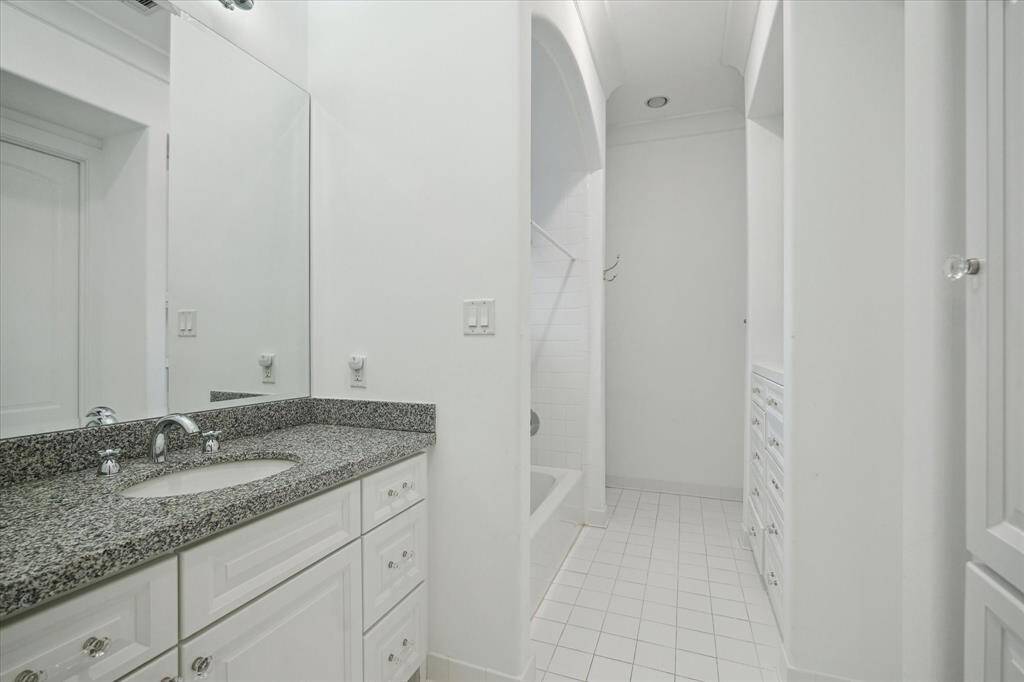 The secondary bathroom featuring elegant granite countertops, ample storage, and a bright, airy design.
