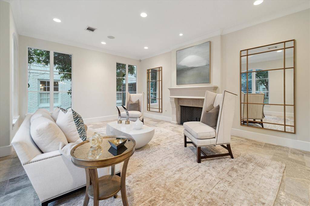 The bright and inviting formal living room with large windows, neutral tones, and a cozy fireplace creating the perfect place for gathering.