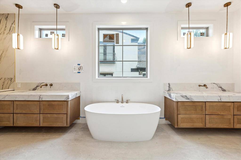 Two vanities with Quartz countertops, abundant storage, and additional counter space flank an oval soaking tub.