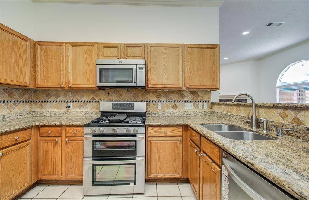 Granite counters, mosaic backsplash and a stainless double-oven gas range elevate everyday cooking.