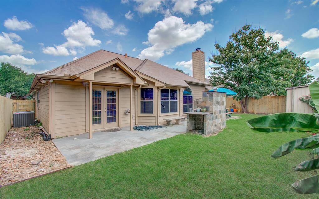 Rear elevation, French doors open to a wide concrete patio and built-in stone grill for weekend cookouts.