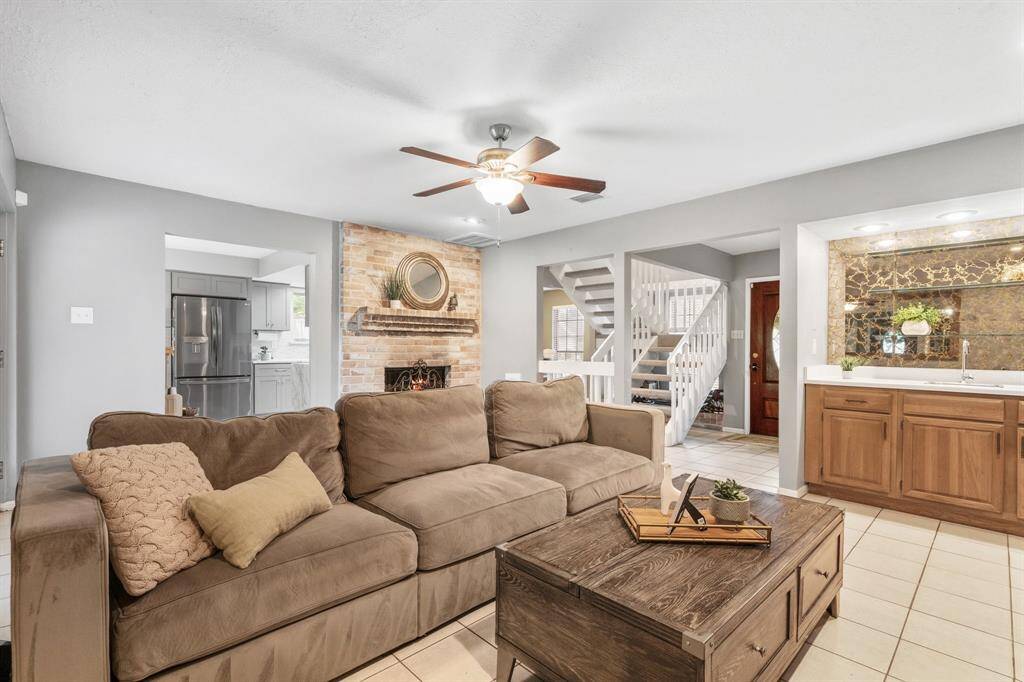 The living room offers views of the kitchen breakfast area, the staircase, and a bar.