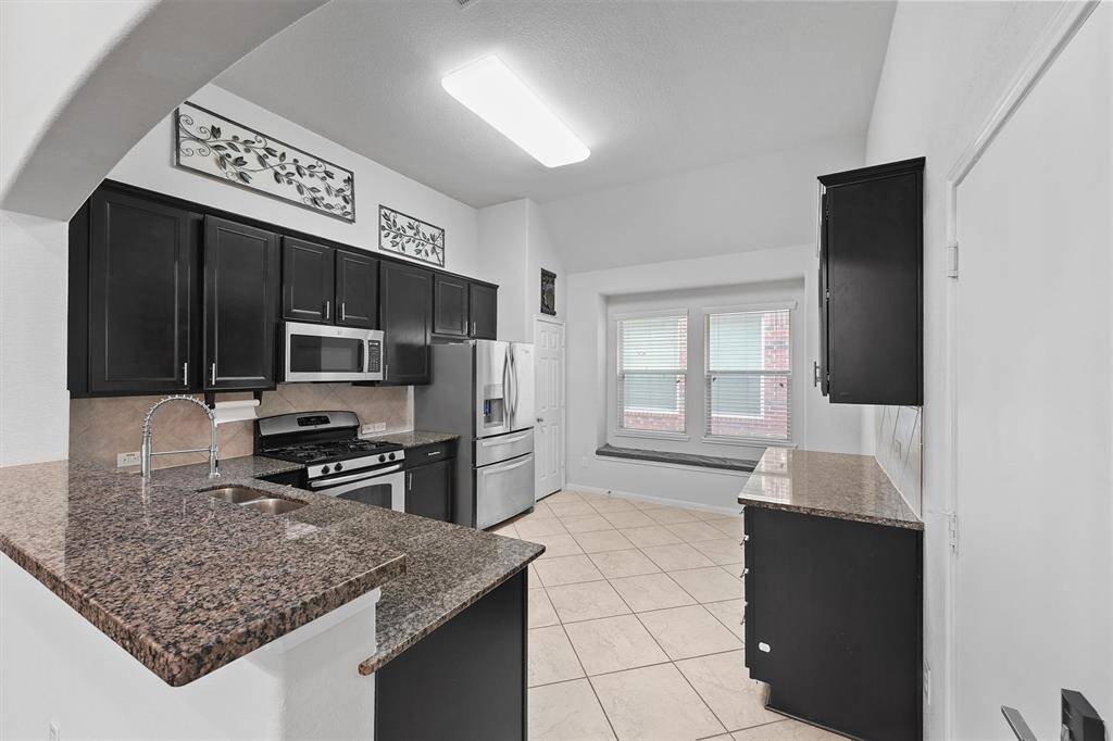 The kitchen features granite countertops, gas cooking, stainless appliances, and a charming window seat for extra dining or lounging space.