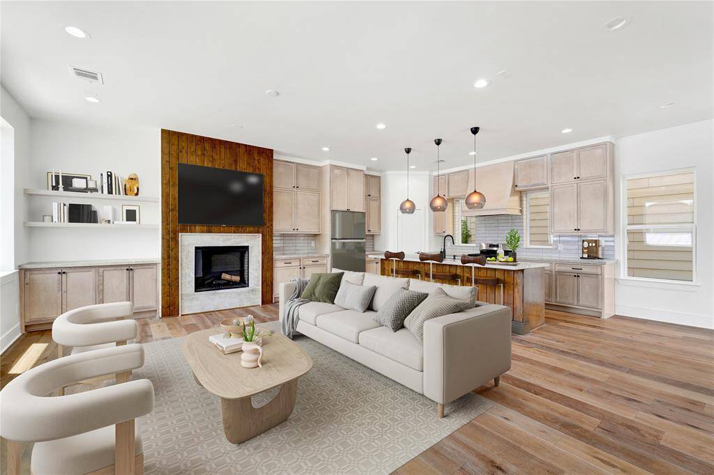 Open concept living and kitchen with a large island, gas fireplace and ample natural light from multiple sides. This photo is virtually staged.