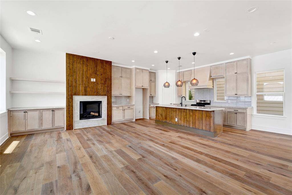 Open concept living and kitchen with a large island, gas fireplace and ample natural light from multiple sides.