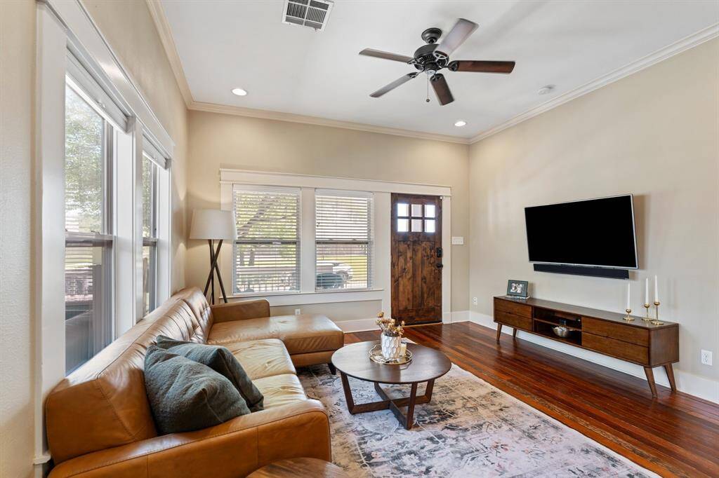 Natural light floods this spacious living room with custom trim work, built-in surround sound, and a cozy, welcoming vibe anchored by rich reclaimed wood floors.