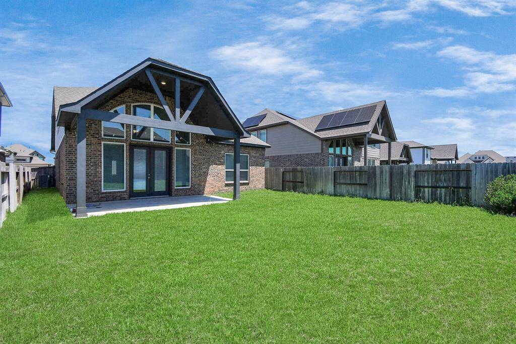 Enjoy outdoor living in the large backyard, featuring a covered patio with high ceilings and trusses