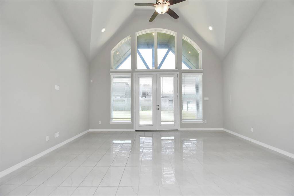 The high ceilings enhance the room's open and airy feel, while the continuous white tile flooring provides a seamless and elegant look