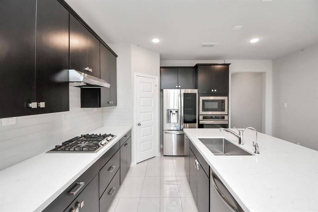 The modern kitchen, featuring sleek cabinetry and perfectly complements the living area's contemporary design. Smart Fridge stays in the home!