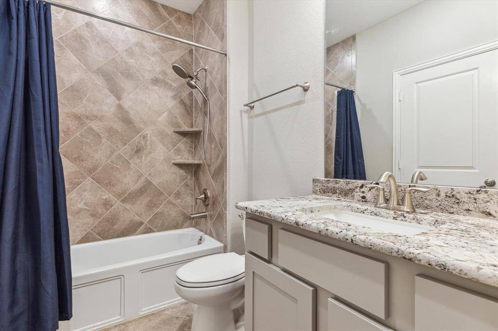 En-suite bath with tub shower combo has granite vanity top, and plentiful storage.